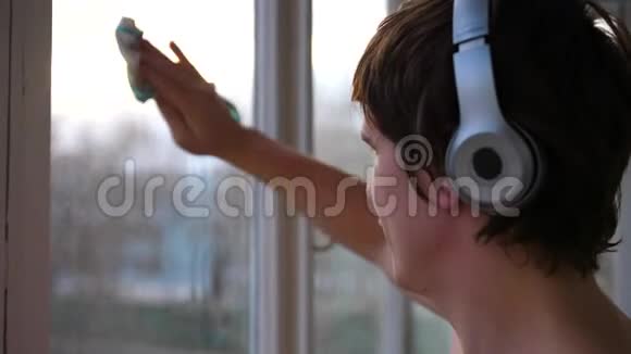 一个带着耳机听音乐在公寓里洗窗户的人窗户清洁器视频的预览图