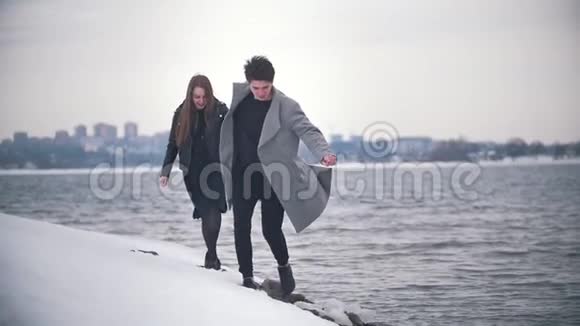 快乐的年轻夫妇在雪地的河边奔跑视频的预览图