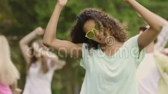 迷人的混血女人摇动头发随着音乐跳舞微笑着拍照视频的预览图