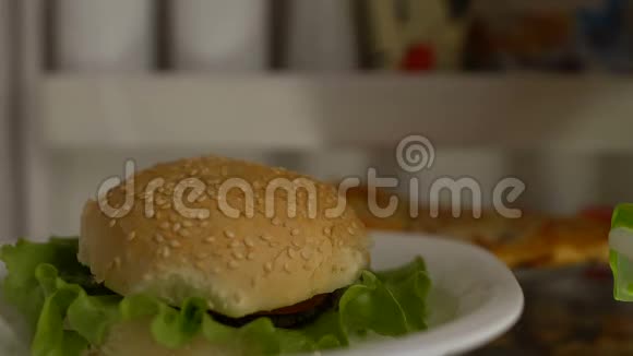 饥肠辘辘的人从冰箱里取出汉堡包咀嚼食物减肥失败垃圾食品视频的预览图