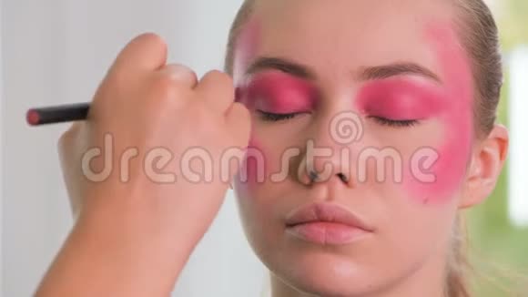 时尚模特准备拍摄化妆师用手在模特脸上涂化妆品视频的预览图