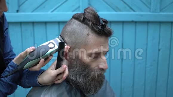 女理发师为户外留白的有魅力的男子剪发电动剃须刀和梳子视频的预览图