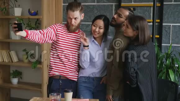 快乐的多民族团队在现代阁楼办公室自拍Hipster男子手持智能手机带着自己的肖像视频的预览图