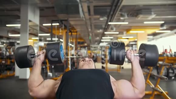 肌肉健美运动员在健身房用哑铃做运动项目视频的预览图
