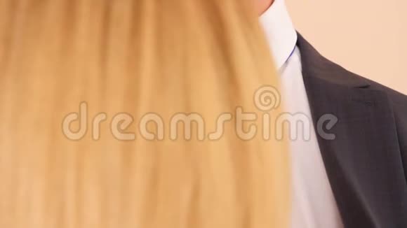 4k慢动作男人衣领上口红一个金发女人正在亲吻一个穿西装和白衬衫的男人留下痕迹视频的预览图