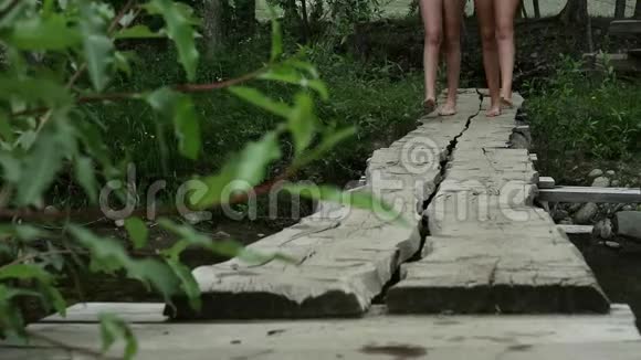 少年腿沿着一座狭窄的木桥走过一条山河野营和冒险概念视频的预览图