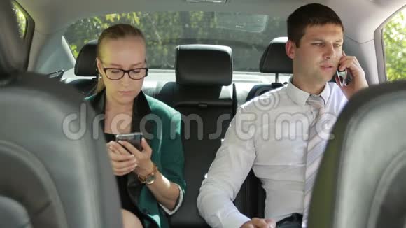 两个坐在车后座的商人用电话视频的预览图