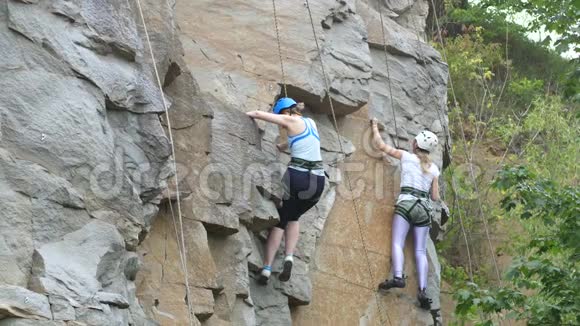 两个女人爬上岩石特写镜头两个女孩岩石绿树视频的预览图