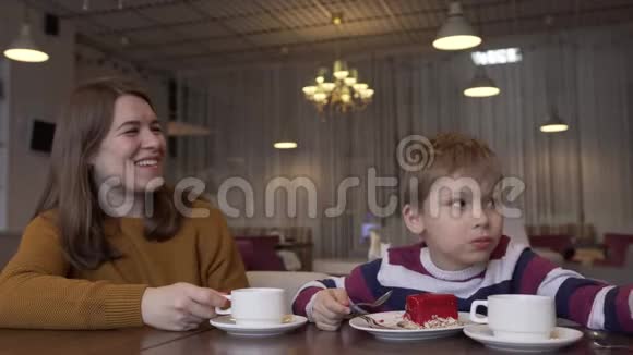 有趣的小男孩和美丽的年轻母亲喝茶吃蛋糕视频的预览图