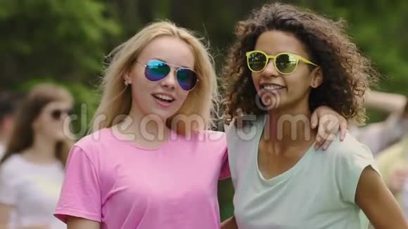 年轻漂亮的女人戴着黄色太阳镜和朋友跳舞在公园放松视频的预览图