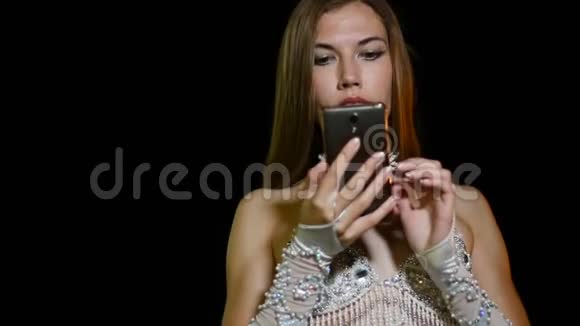 穿着东方民族服装的年轻女舞者晚上在户外使用智能手机视频的预览图