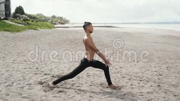 慢动作稳定射击运动赤膊男子在沙滩上做伸展运动视频的预览图