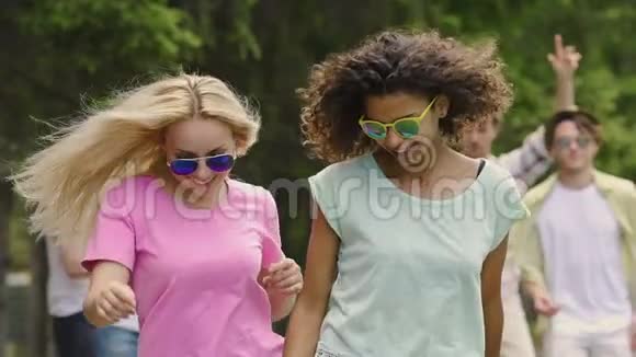 金发和黑发女孩跳舞在公园的音乐会上闲逛快乐视频的预览图