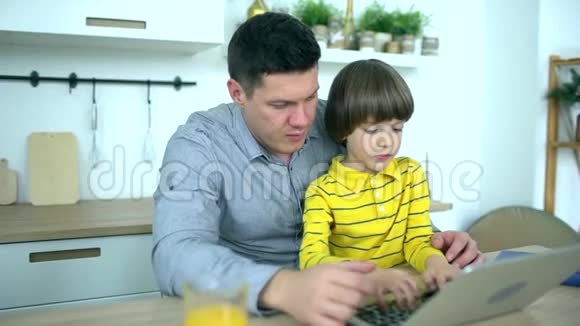 父子使用笔记本电脑英俊的父亲看着电脑家里有个很可爱的儿子父亲节慢动作视频的预览图