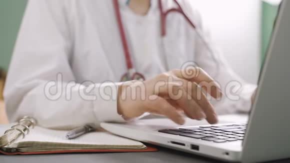 医生在办公桌上工作他正在笔记本电脑上打字前景上的听诊器医疗保健概念视频的预览图