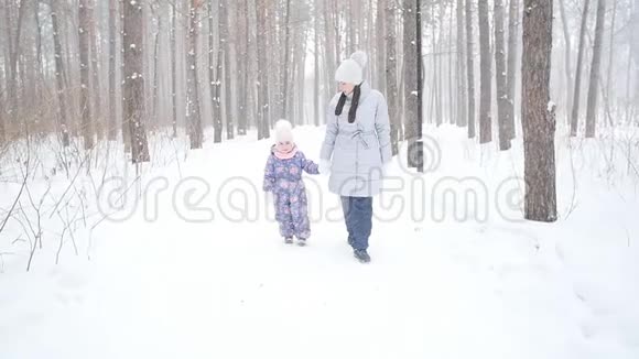 母亲和女儿在雪林或公园散步视频的预览图