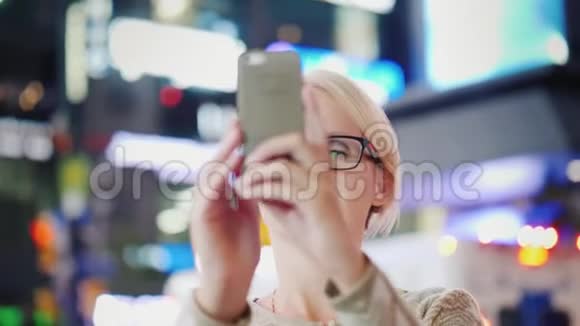 女人是大城市的游客带着仰慕的照片用智能手机拍摄纽约时代广场视频的预览图