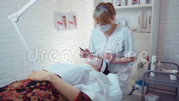 美容师将面膜敷在美容院年轻女性的脸上视频的预览图
