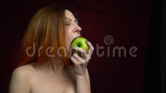 红发女人慢慢地从一个绿色的大苹果上咬下一块视频的预览图
