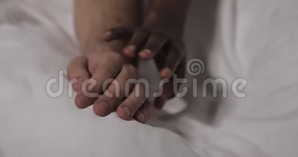 恋爱中的多民族夫妇躺在床上快关门男人的手躺在床上女人的手在抚摸它视频的预览图