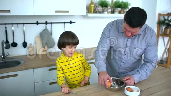 父亲蛋做煎蛋可爱的父亲和非常可爱的小男孩在厨房做早餐父亲视频的预览图