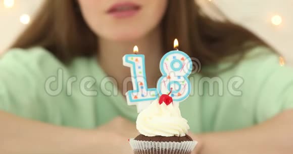 美丽的白种人女孩在蛋糕上吹着18支蜡烛视频的预览图