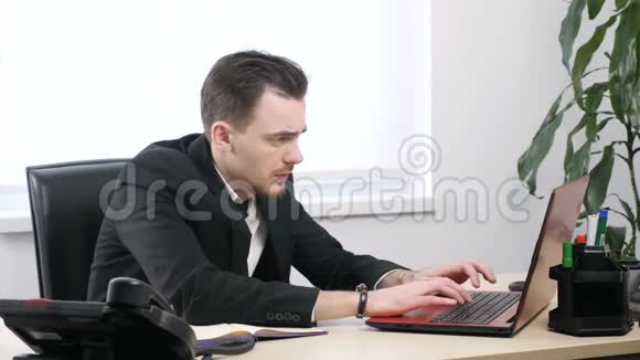 穿西装的年轻商人厌倦了在笔记本电脑上工作抓住了他的头60英尺视频的预览图