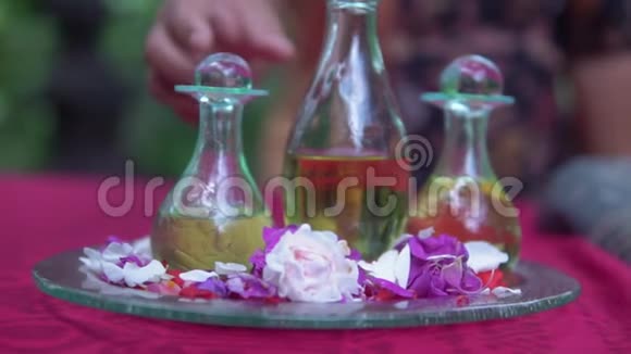 三个带有芳香按摩油的玻璃洋葱瓶在玻璃圆形托盘上按摩治疗师手部特写镜头视频的预览图