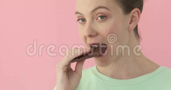女人在粉红色背景下吃巧克力视频的预览图