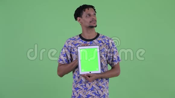 一位年轻英俊的非洲小伙子正在看数字平板电脑视频的预览图