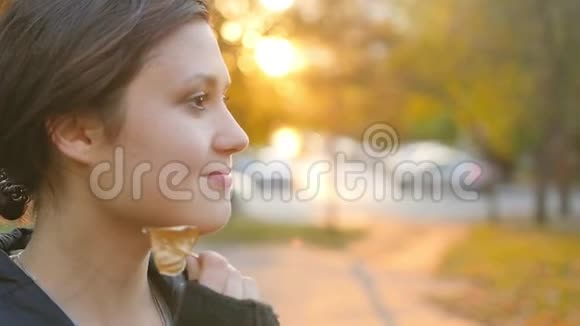 一位可爱的年轻女子在日落时在公园里欣赏秋天的肖像布鲁内特在秋天公园的背景视频的预览图