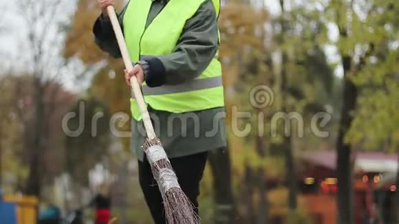 穿制服的女看门人在公园里扫落叶低收入工作危机视频的预览图