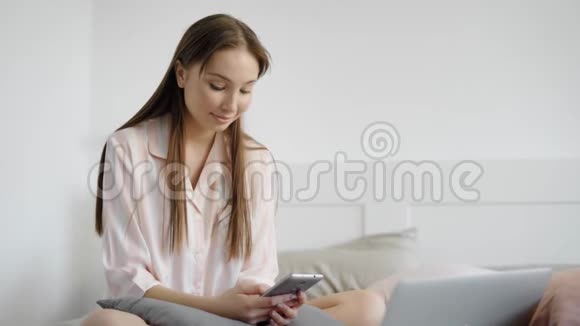 布鲁内特女士正在她的卧室里上网用现代智能手机在社交网络上查看新闻视频的预览图