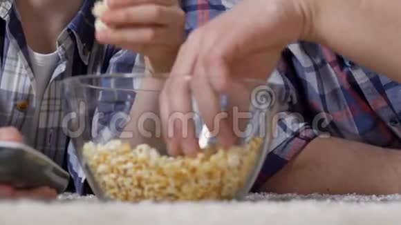 男性在看电视时从玻璃碗里拿出爆米花吃不健康的食物视频的预览图