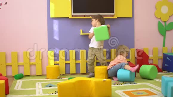快乐的孩子在室内操场上玩柔软的多色积木学前儿童体育活动视频的预览图