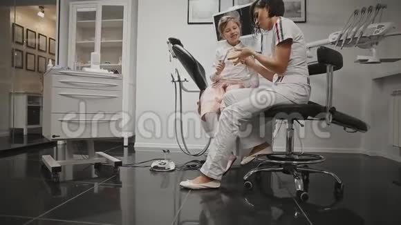 在牙科医生办公室里一个正在学习刷牙的小女孩的X光头正畸医生视频的预览图
