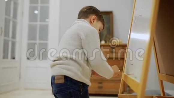 房子客厅里的小男孩在黑板上画着一个孩子画记号学前教育视频的预览图