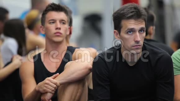 两个有魅力的男人在体育馆听教练训练视频的预览图