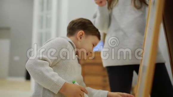 小男孩和妈妈在她的客厅房子油漆板上的标记一个孩子画休闲幸福家庭视频的预览图