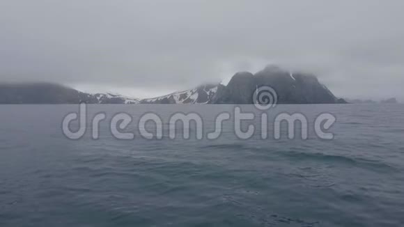 从帆船经过多雪的岛屿和山多云的海洋中可以看到风景视频的预览图
