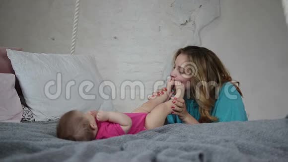美丽的母亲亲吻新生婴儿的脚视频的预览图