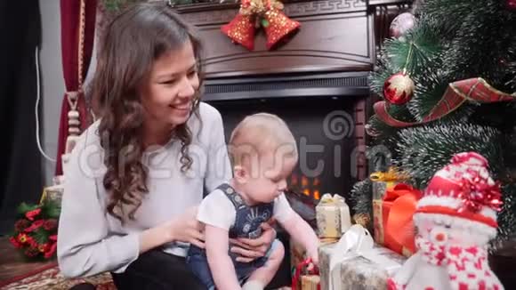 一位年轻的母亲和一个年轻的儿子在壁炉旁修圣诞树圣诞快乐假日快乐视频的预览图