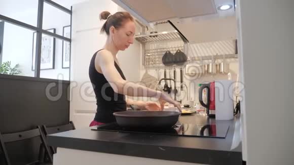 年轻女子站在厨房的炉子旁为家人准备早餐生活方式视频每天视频的预览图