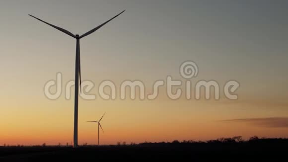 日落时风力发电机和树木的剪影视频的预览图