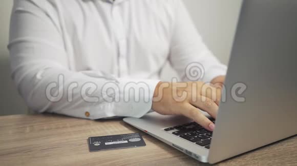 网上购物概念男人手拿信用卡用笔记本电脑信用卡在桌子上视频的预览图