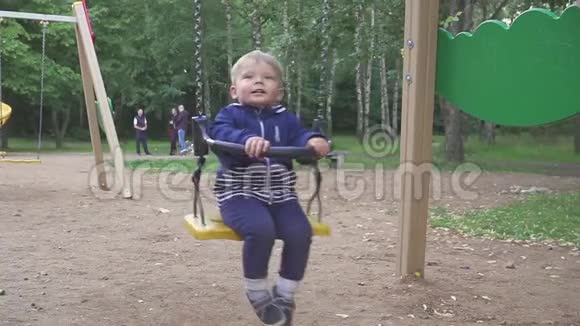 两岁的男孩正在公园里骑秋千视频的预览图