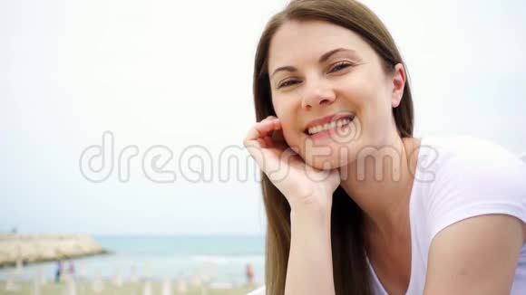 年轻女子坐在海滩上的肖像从地中海吹来的风慢慢地吹着她的头发视频的预览图