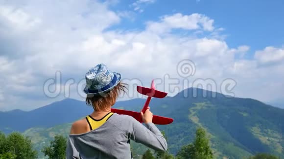 年轻漂亮的女人回到镜头前把飞机的红色模型保存在鲁奇旅行和自由的概念视频的预览图