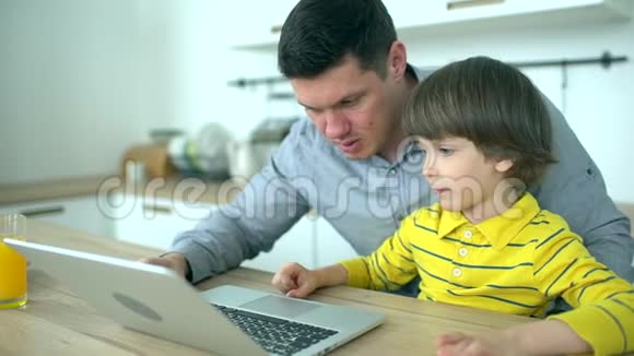 父子使用笔记本电脑英俊的父亲看着电脑家里有个很可爱的儿子父亲节慢动作视频的预览图