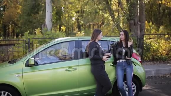 两个朋友在路边谈论绿色汽车附近视频的预览图